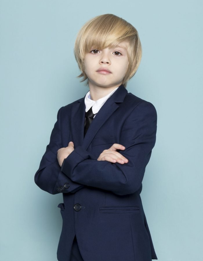 a front view cute business boy in blue classic suit posing looking into the camera business work fashion on the blue background